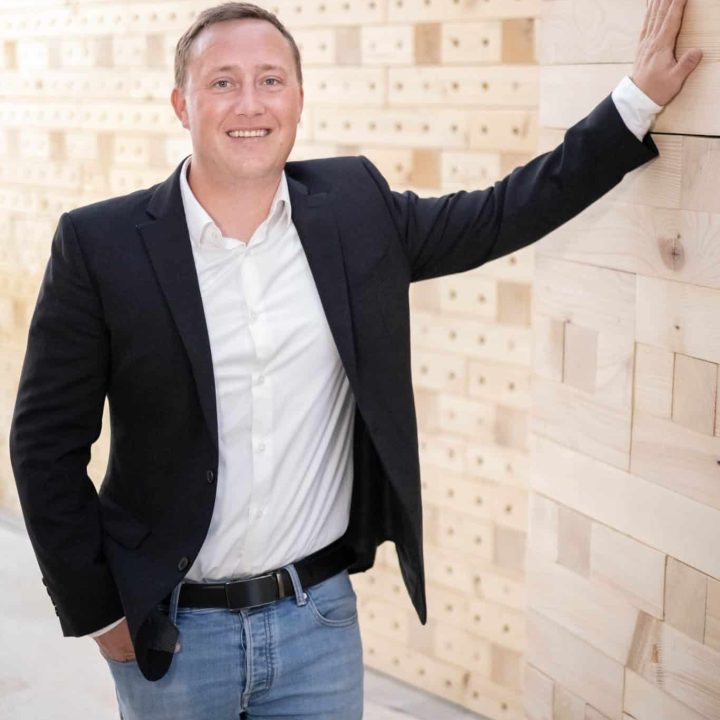Porträt von Vorstand Max Wörner vor einer Wand in Massivholzbauweise